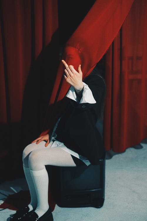 A person sitting on a chair with a red curtain