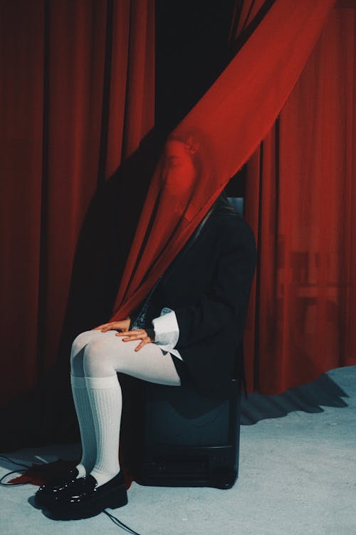 A person sitting on a chair with a red curtain