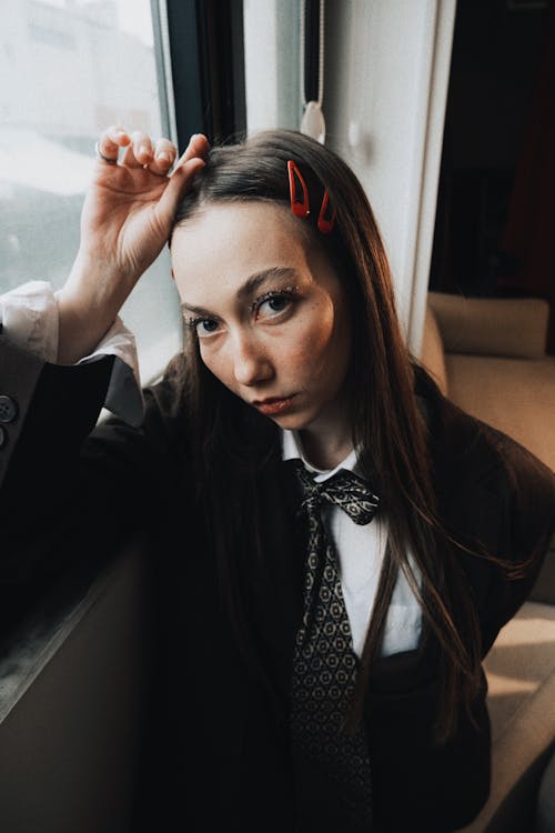 A woman in a suit and tie leaning against a window