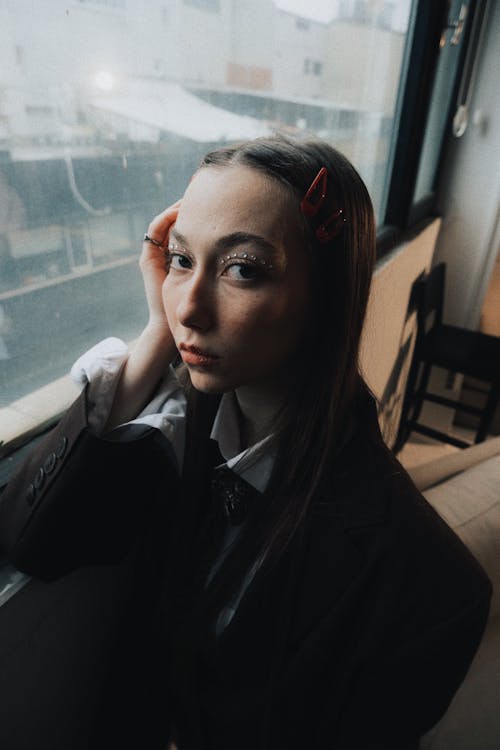 A woman with a red bow on her head is looking out the window