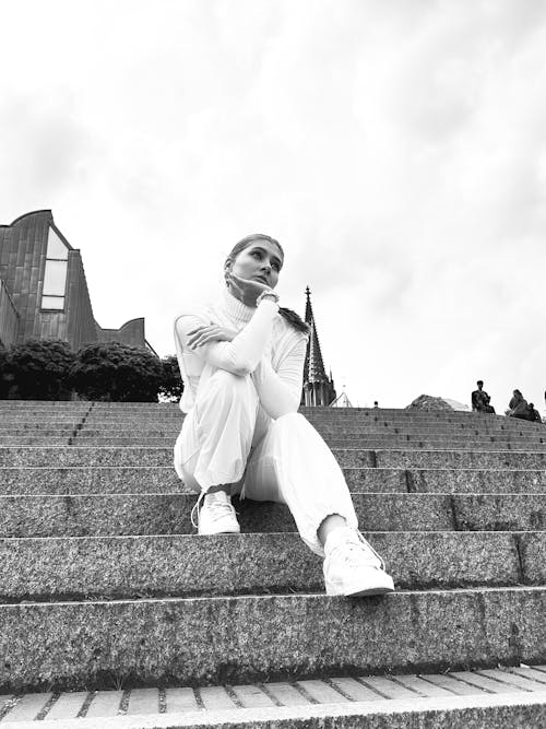 A woman in white sitting on some steps