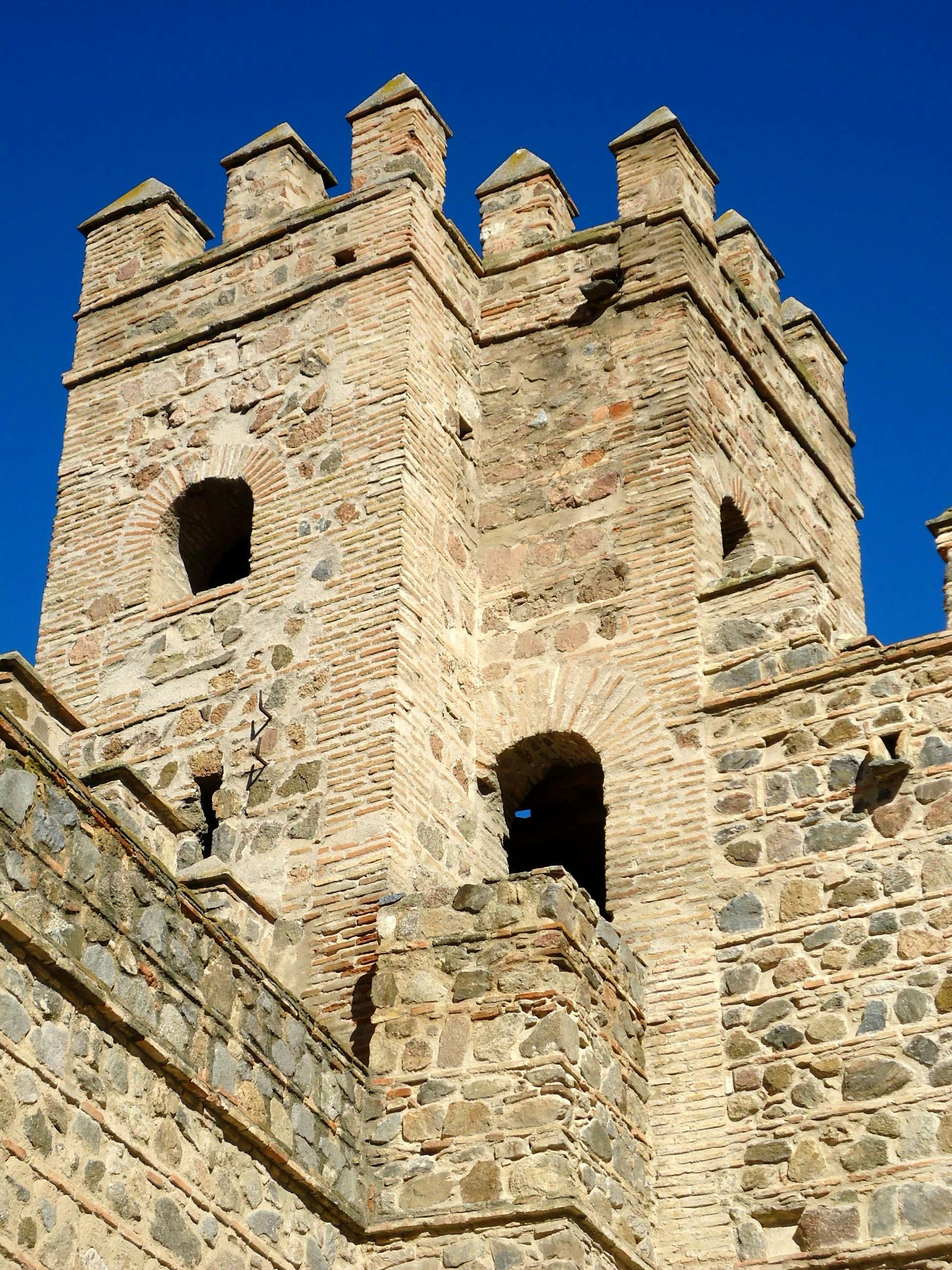 Medieval stone tower in Toledo, Spain, showcasing historic architectural design against clear blue sky.