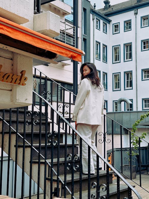 A woman in a white suit is standing on the stairs