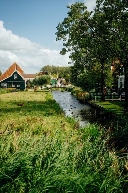 Scenic view of a quaint Dutch village with green houses by a serene river.
