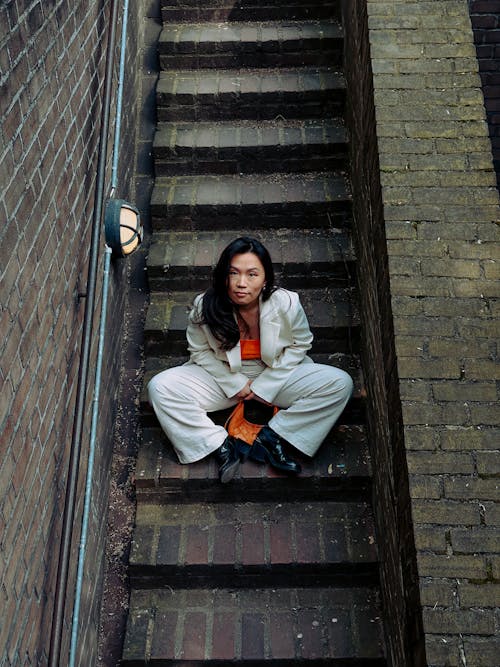 A woman sitting on the stairs in an orange outfit