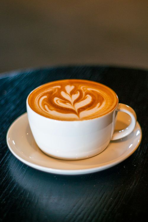 Free Cappuccino with beautiful froth art in a white cup, sitting on a saucer. Stock Photo