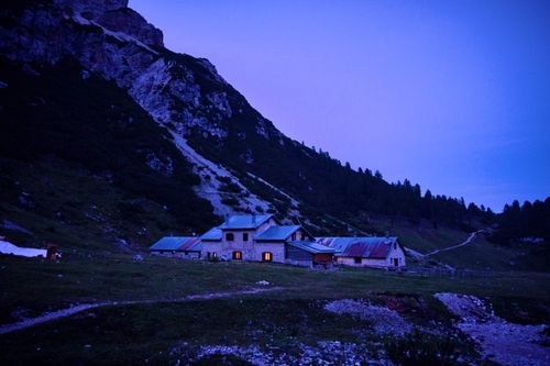 Free Twilight descends on rustic houses in the Italian Alps, Spormaggiore, enveloped by serene mountain landscapes. Stock Photo