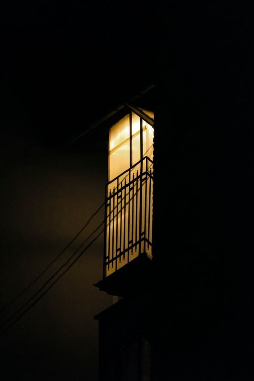 Free A softly illuminated balcony in an urban setting, surrounded by darkness. Stock Photo