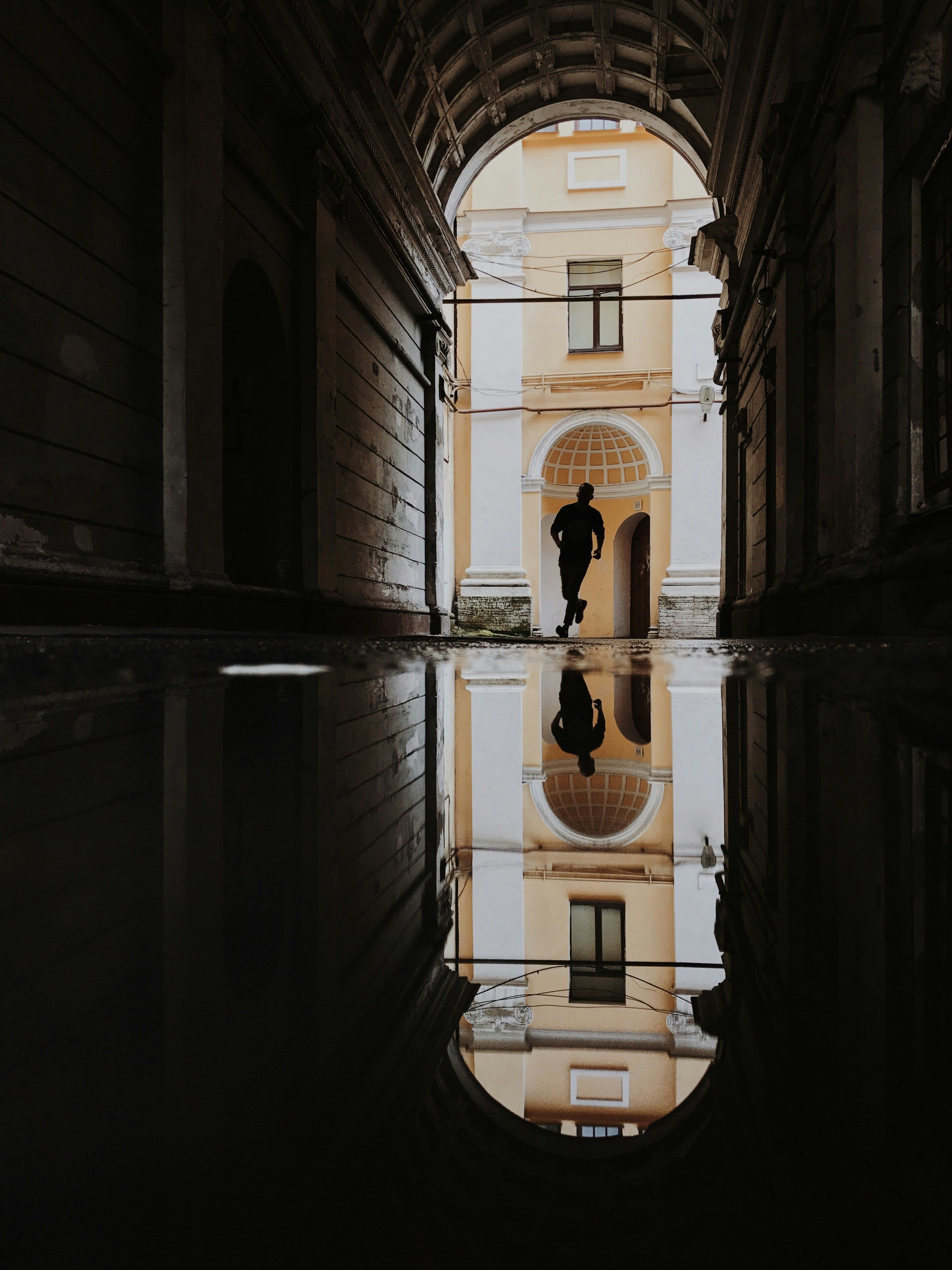 Silhouette of a person running in an alleyway with reflections in Saint Petersburg, Russia.