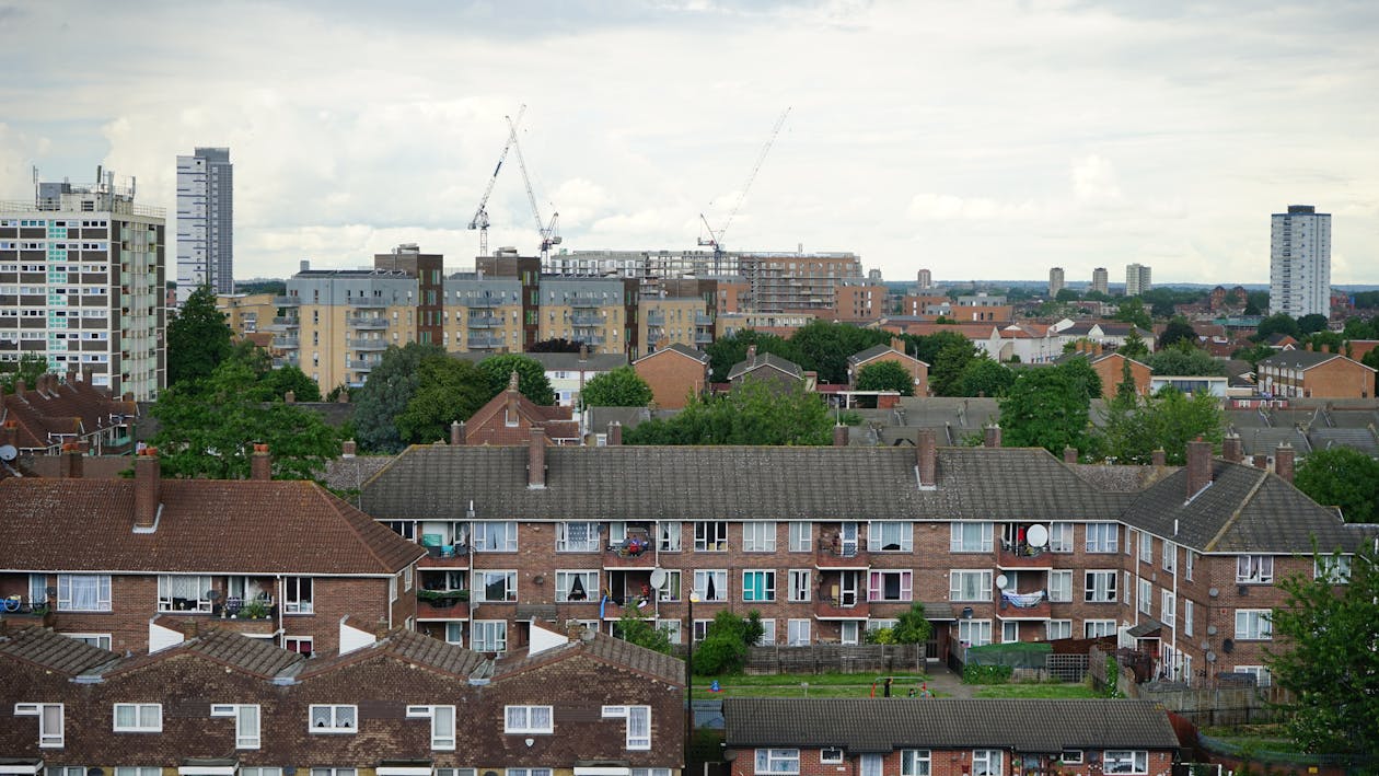 Free Brown And White Wall Paint Houses Beside Green Trees Near High Rise Building Stock Photo