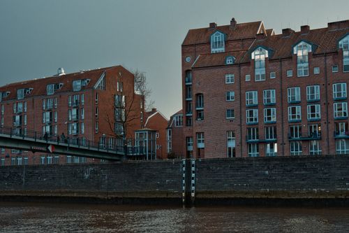 Free Charming brick buildings line the canal in Bremen, Germany, showcasing urban architecture. Stock Photo