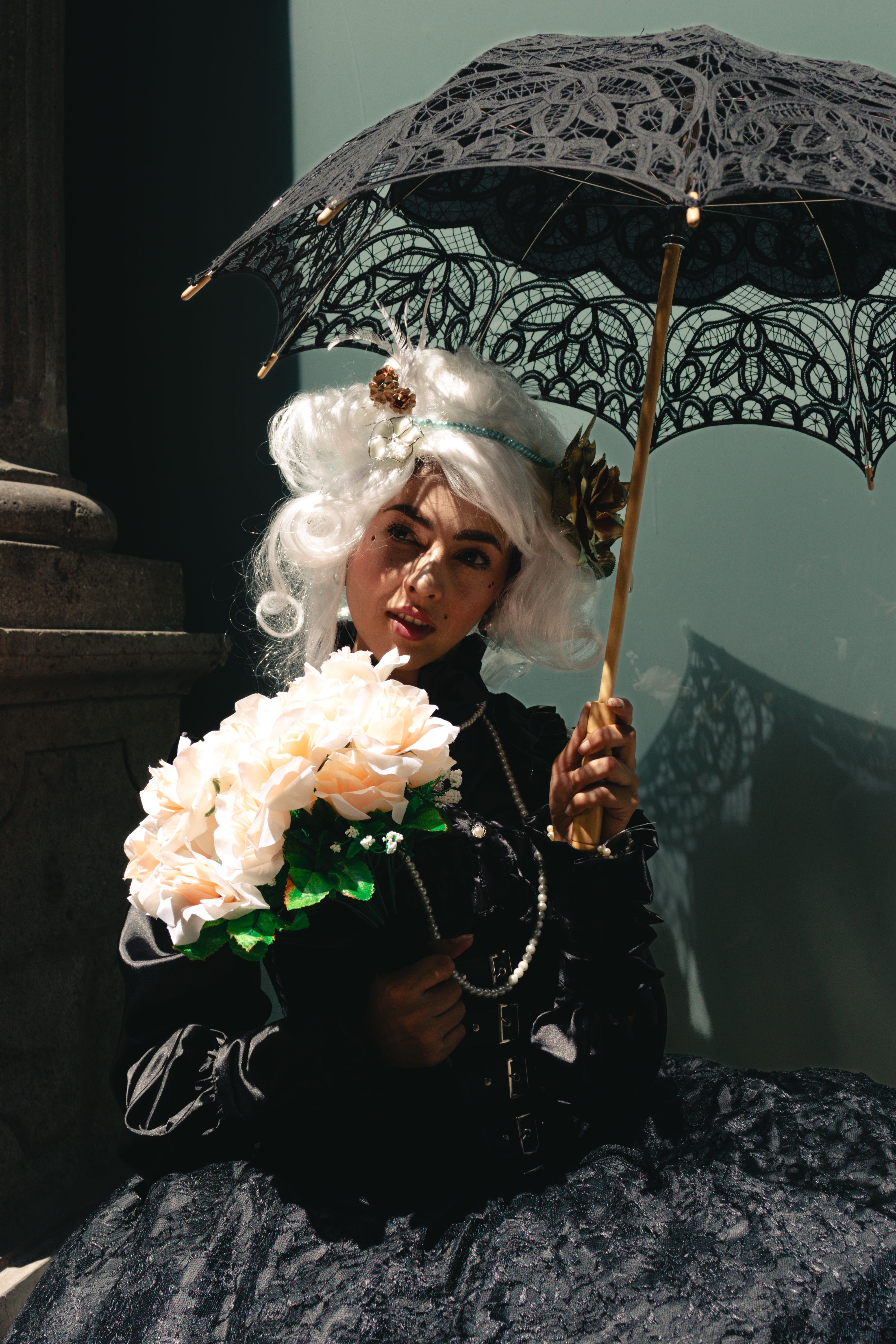 Graceful woman in vintage attire with parasol in Ciudad de México, capturing elegance.