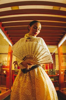 A woman in traditional dress poses with a lace fan inside a Mexican museum display.