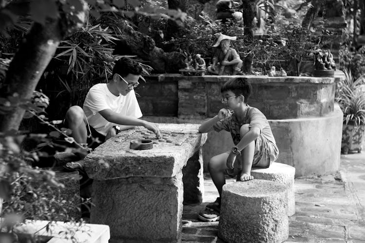 Father Teaching His Son How To Play A Board Game