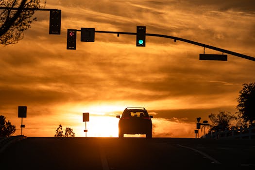 Car silhouette under a traffic light with a stunning sunset backdrop in Highland, CA.