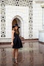 穿着黑色连衣裙的优雅女子在装饰性建筑物前摆姿势