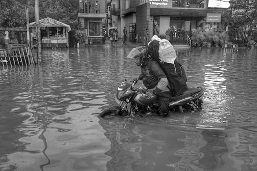 A motorcyclist rides through a flooded street in Kolkata, India during a natural disaster.