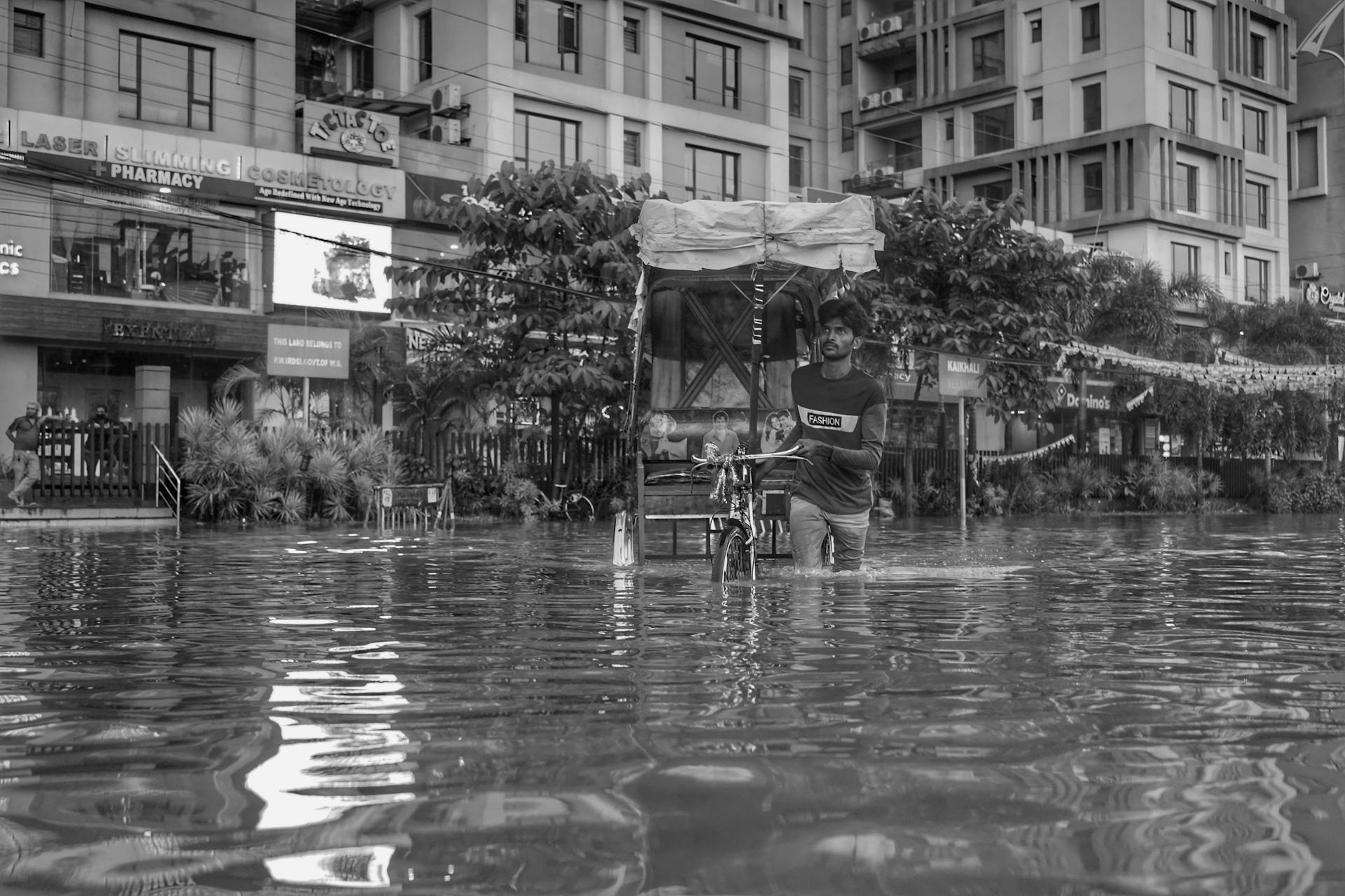 A Man Pushing a Rickshaw on a Flooded Street