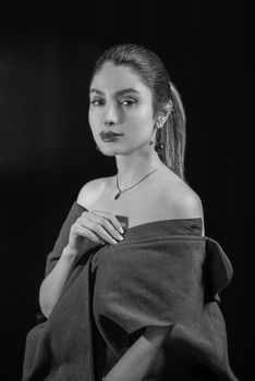 Black and white studio portrait of an elegant woman wearing jewelry and a stylish outfit.