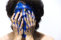 这幅引人注目的艺术肖像描绘了一位涂满蓝色油漆的女性，展现了情感与创造力