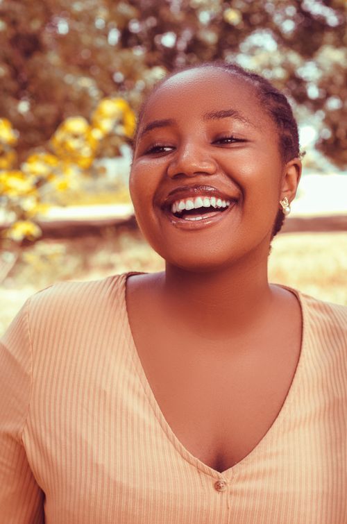 Free Portrait of a smiling woman enjoying a sunny day outdoors in a warm, vibrant setting. Stock Photo