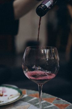Close-up of red wine being poured into a glass at a dinner party setting.