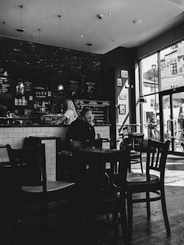 Black and white image of a modern café with people enjoying coffee and conversation.