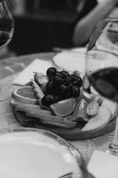 Artistic black and white photo of a fruit platter with wine glasses, showcasing an elegant dining setting.
