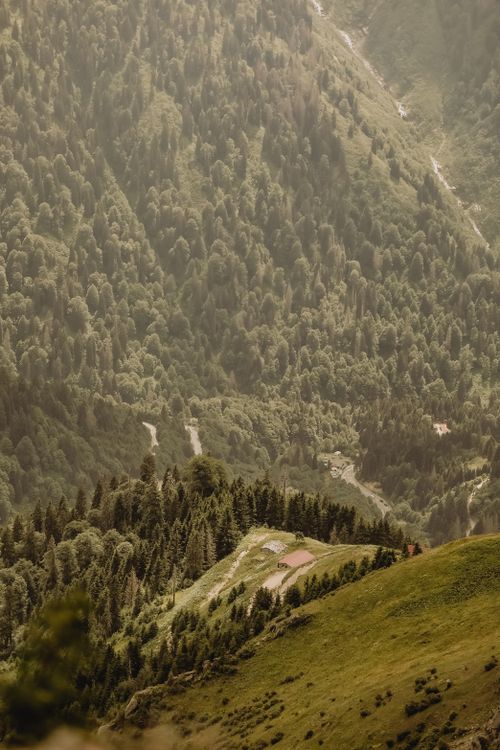 Free Breathtaking aerial view of lush green mountain valley surrounded by dense forests. Stock Photo
