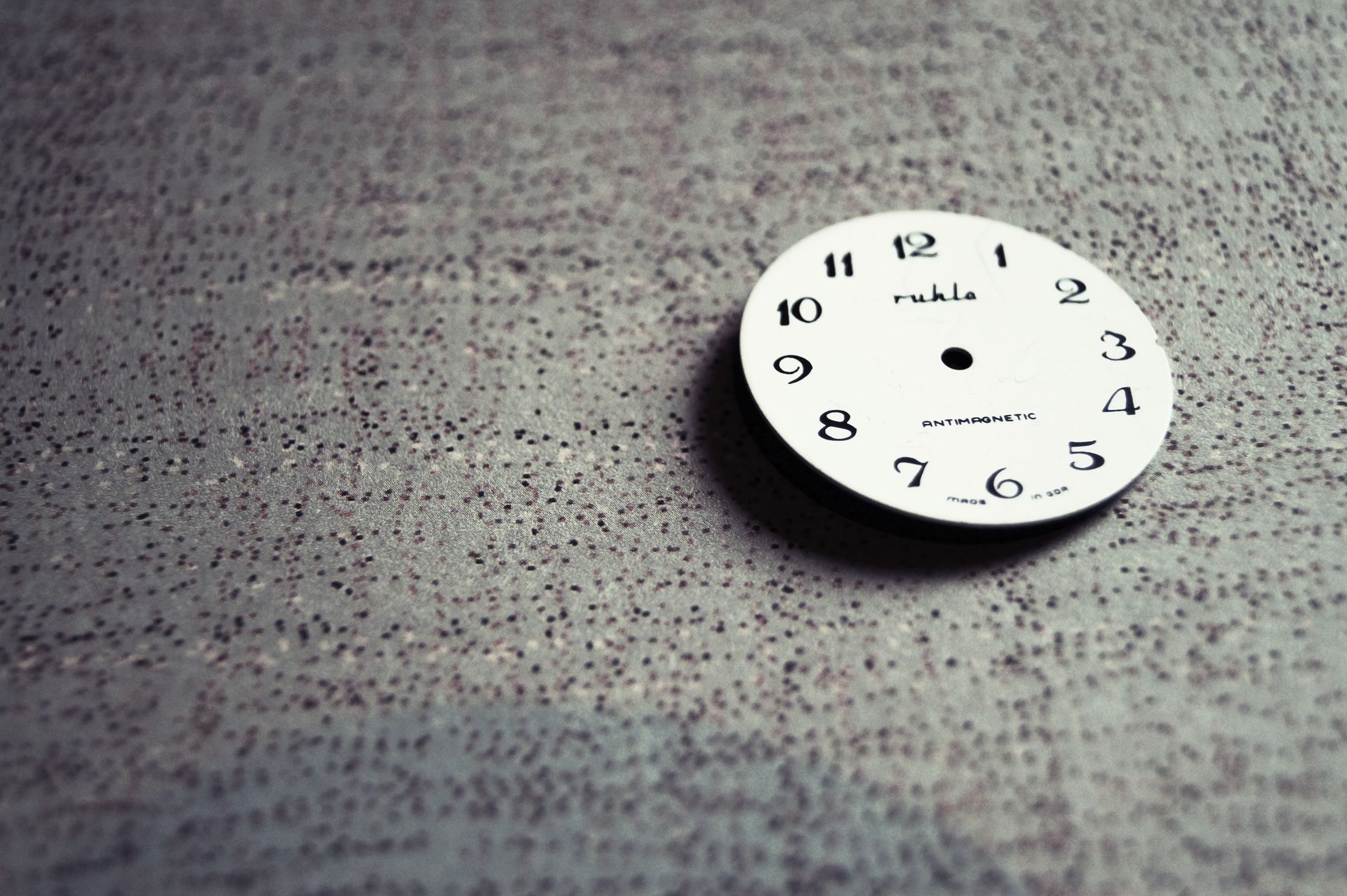 Close-up of a vintage clock face with numbers on a textured background, emphasizing detail.