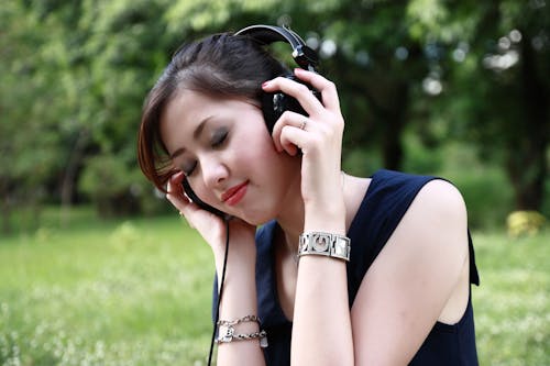 여자가 들고 야외에서 검은 색 유선 된 헤드폰을 착용