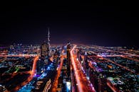 迪拜夜间城市景观的鸟瞰图令人惊叹，凸显了灯火通明的哈利法塔和周围的摩天大楼