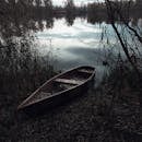 黄昏时分，一艘孤独的独木舟停在波光粼粼的湖边，四周一片静谧