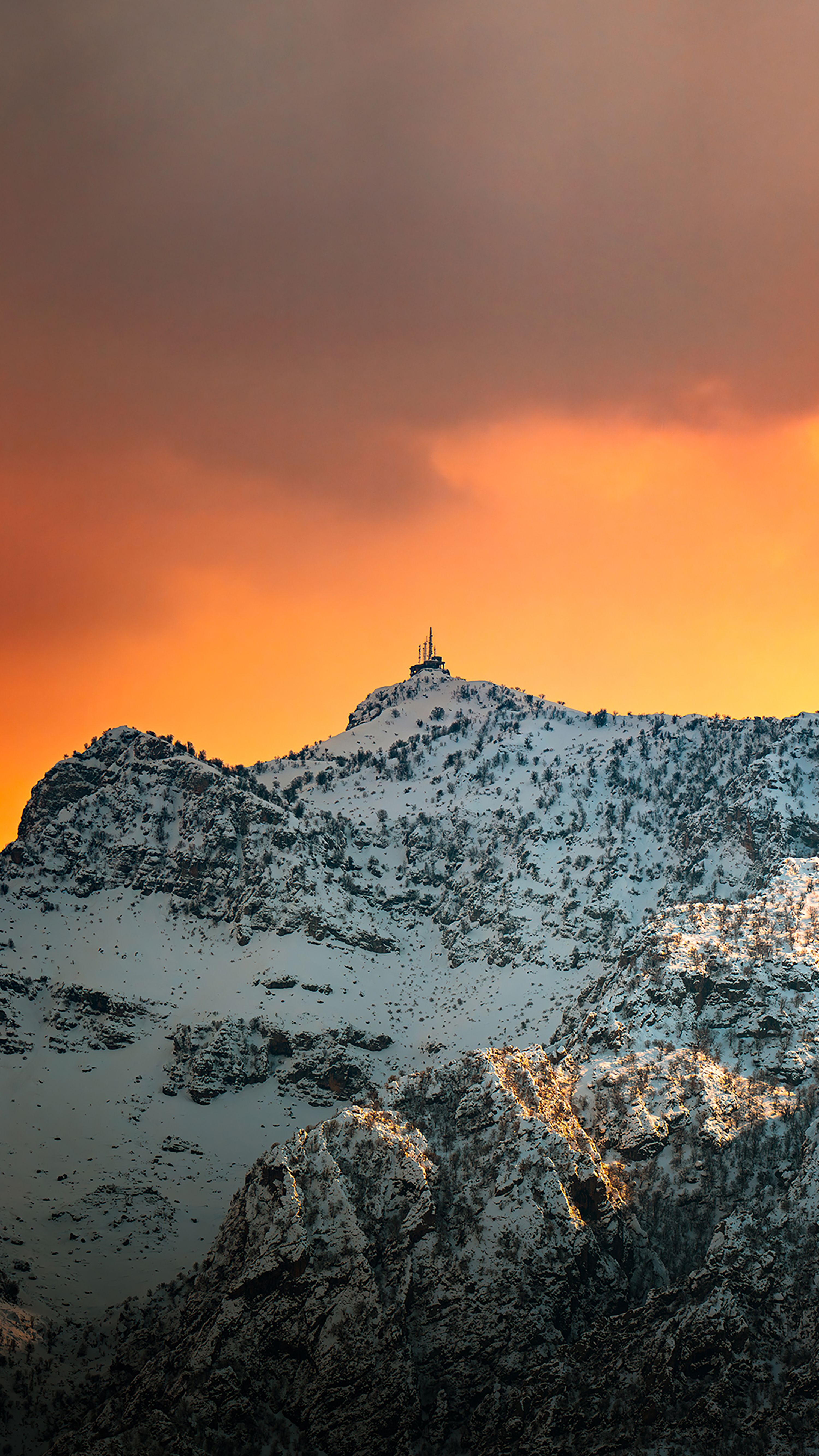 Stunning view of snowcapped mountains at sunset in Duhok, Kurdistan, with dramatic orange skies.