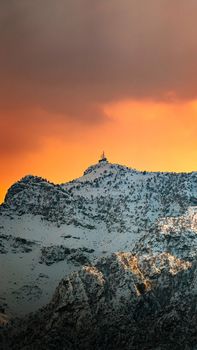 Stunning view of snowcapped mountains at sunset in Duhok, Kurdistan, with dramatic orange skies.