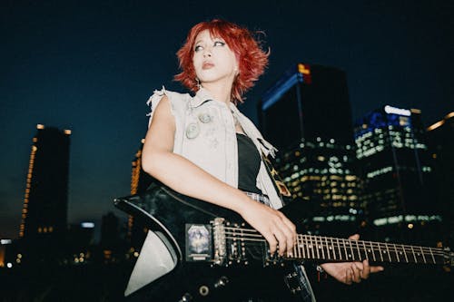 A woman with red hair playing an electric guitar