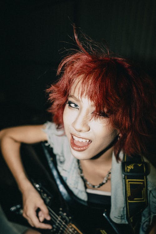 A woman with red hair playing an electric guitar