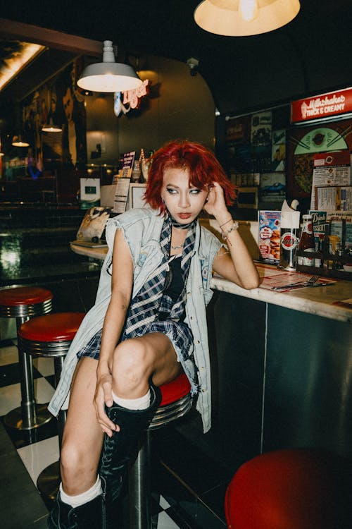 A woman with red hair sitting on a stool in a diner