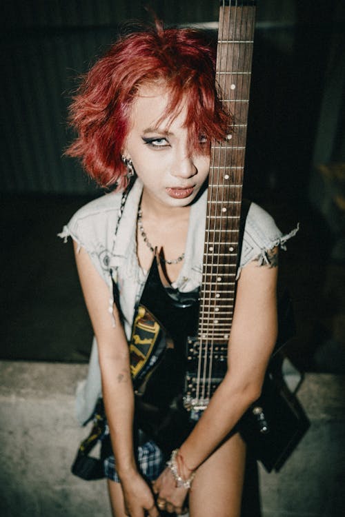 A girl with red hair holding a guitar