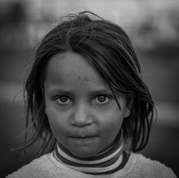 Expressive black and white portrait of a thoughtful young girl outdoors.