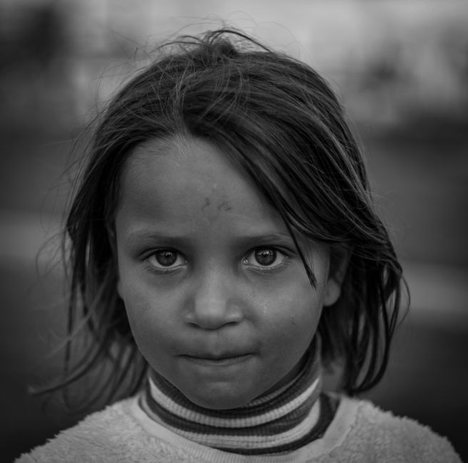 Expressive black and white portrait of a thoughtful young girl outdoors.