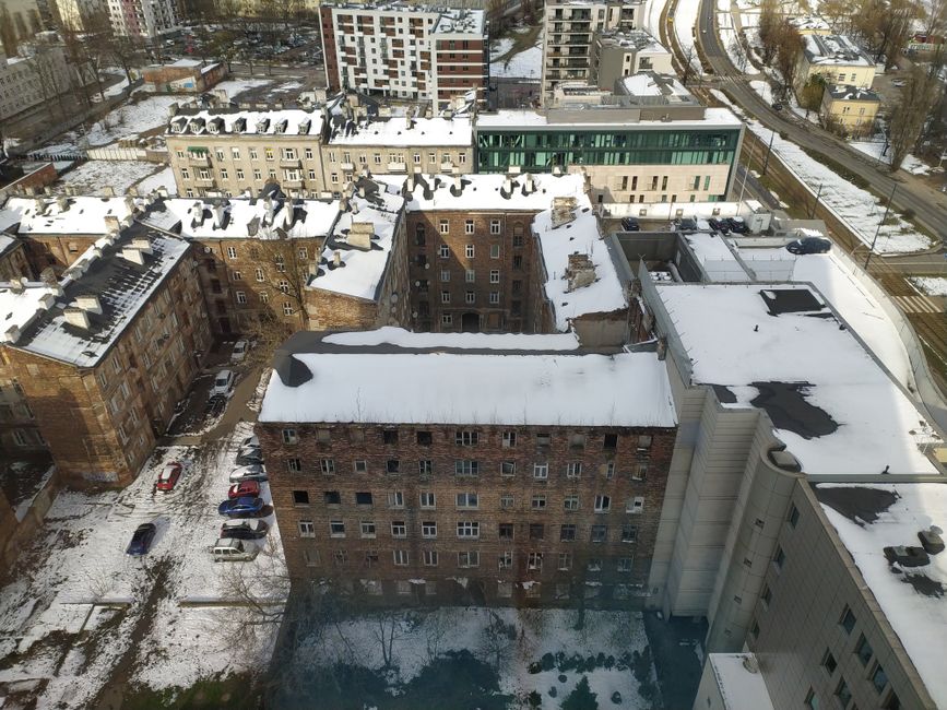 Overhead shot of urban buildings with snow-covered rooftops during winter, showcasing a dense cityscape.