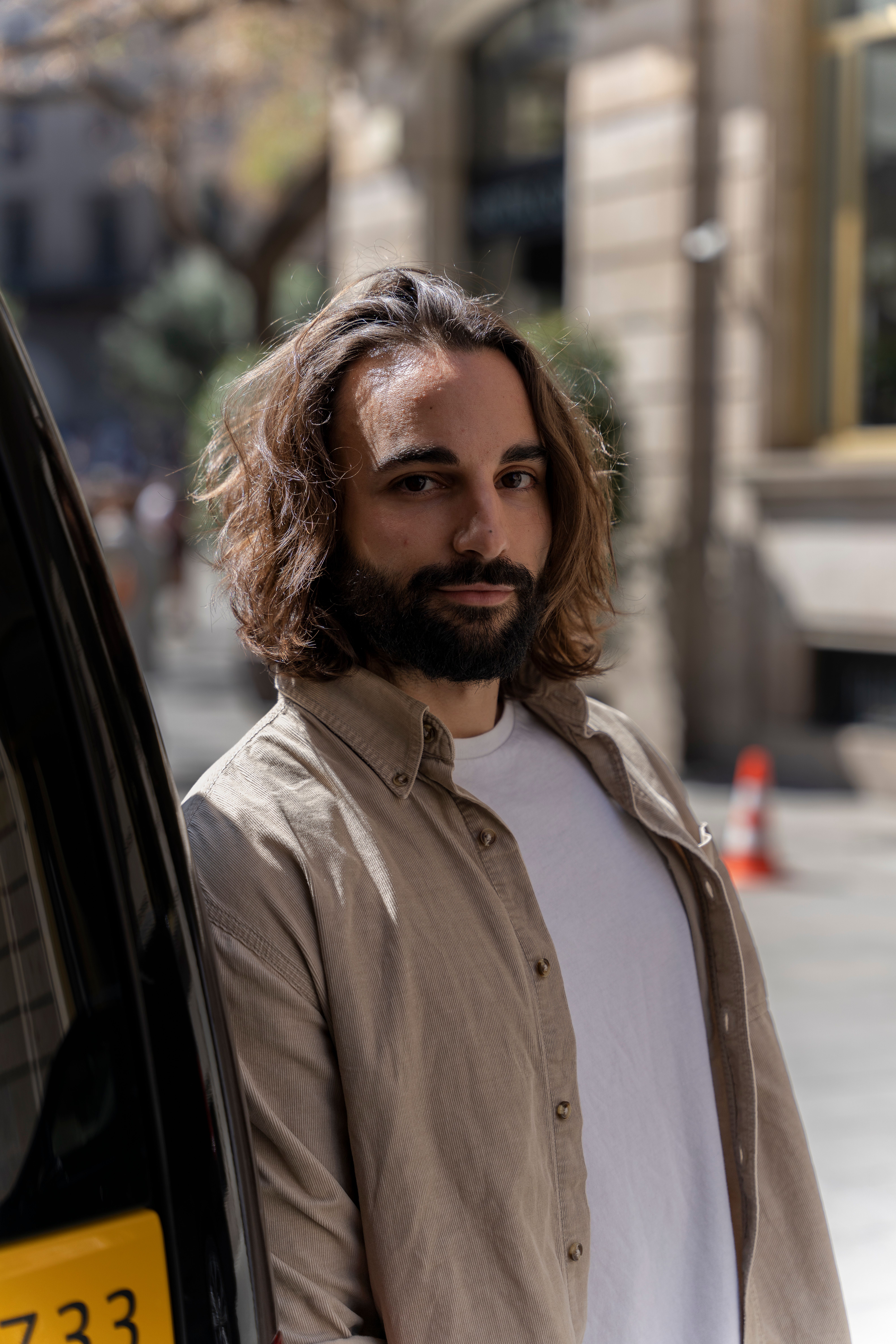 Portrait of a handsome young man with a beard in an urban setting, exuding confidence and style.