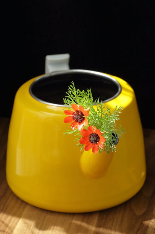 A yellow teapot with a flower in it