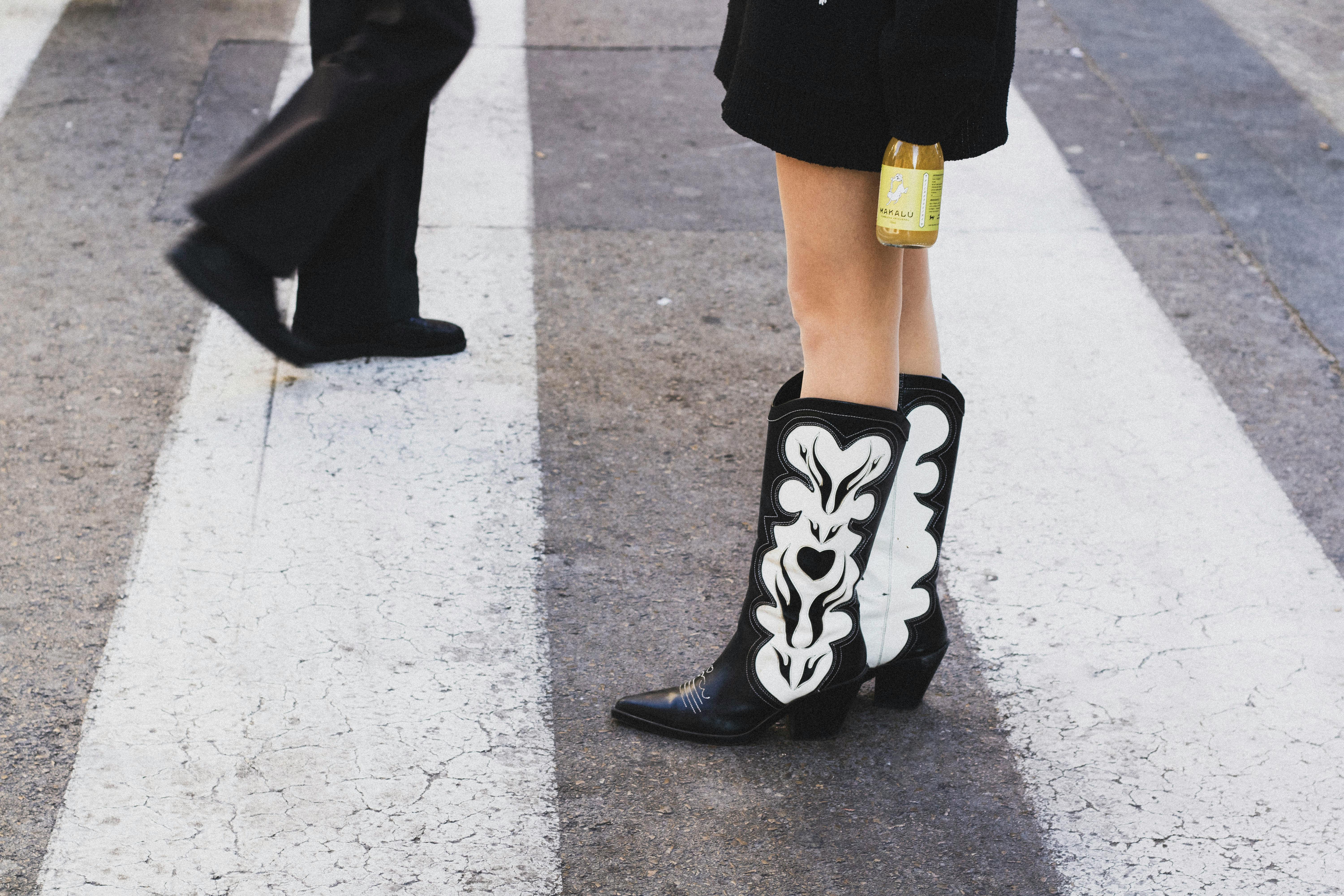 Fashionable cowboy boots on a city crosswalk in Valencia, Spain, showcasing urban style.