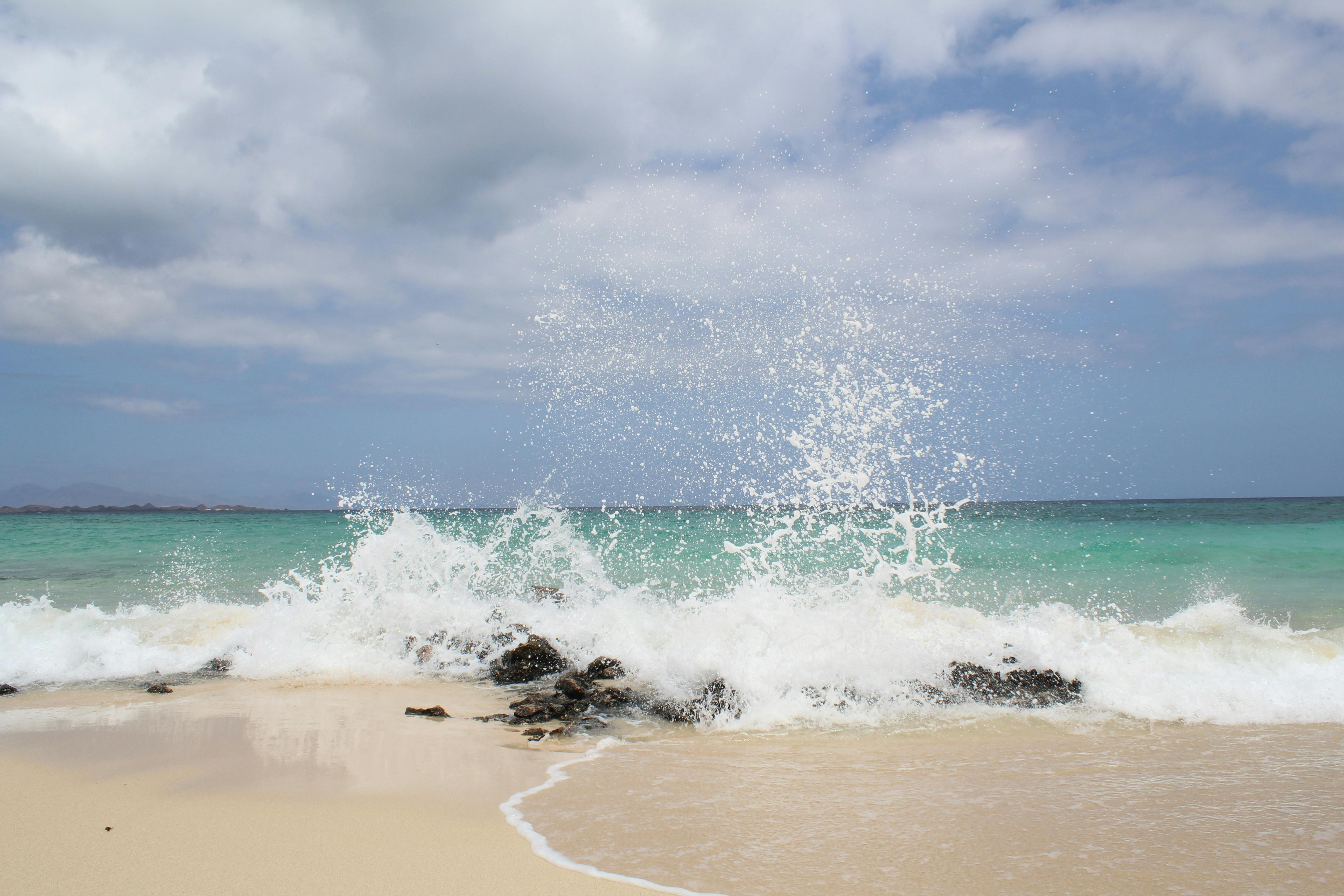 Seawater splashed on rocks on the shore. | Photo: Pexels