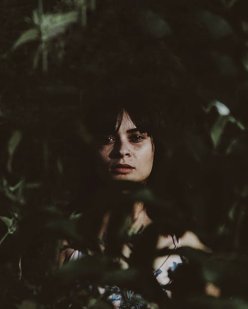 Женщина прячется за зелеными листьями