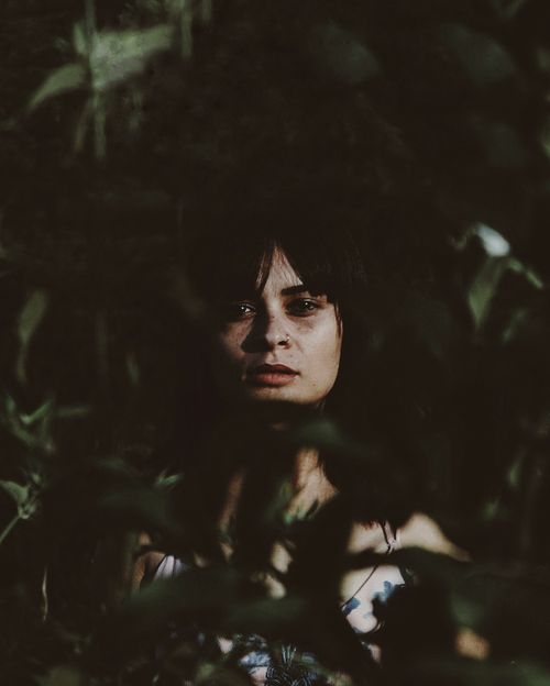 Free Artistic portrait of a woman amidst foliage, creating a mysterious and moody ambiance. Stock Photo