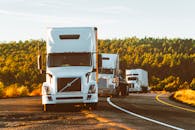 三辆半挂卡车行驶在高速公路上，穿过亚利桑那州的森林景观