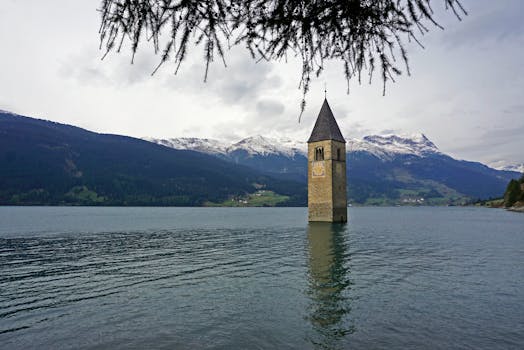 雷西亚湖中淹没的教堂钟楼，坐落在群山环绕的景色里